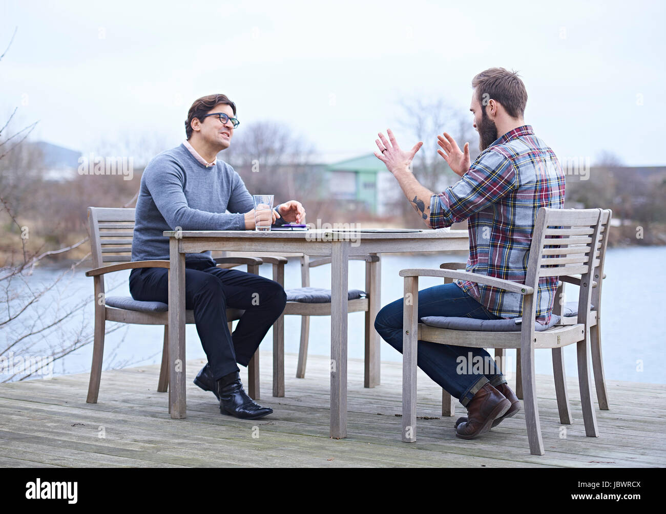 Two male designers having discussion on waterfront outside design ...