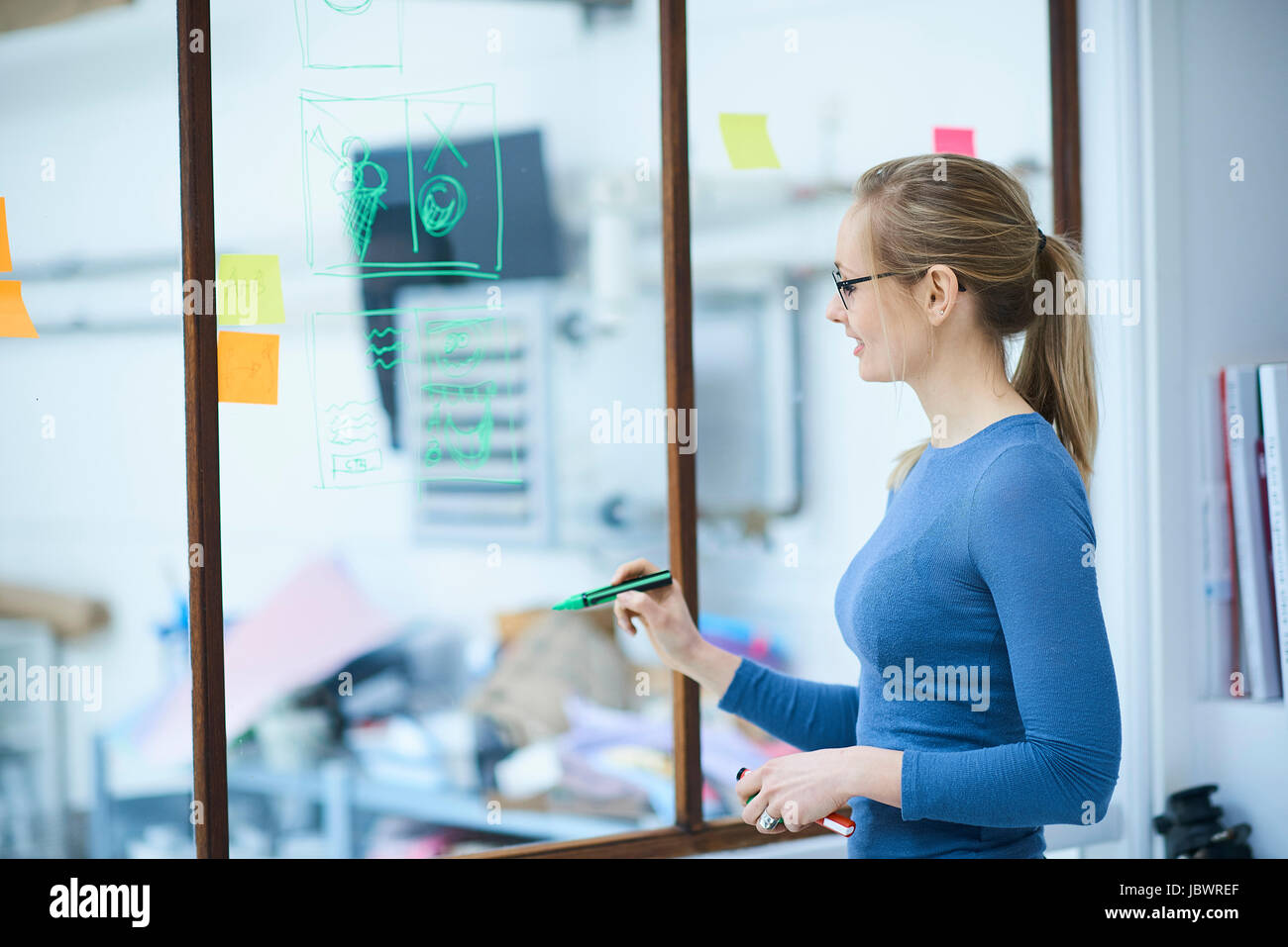 Female designer drawing on design studio window Stock Photo - Alamy