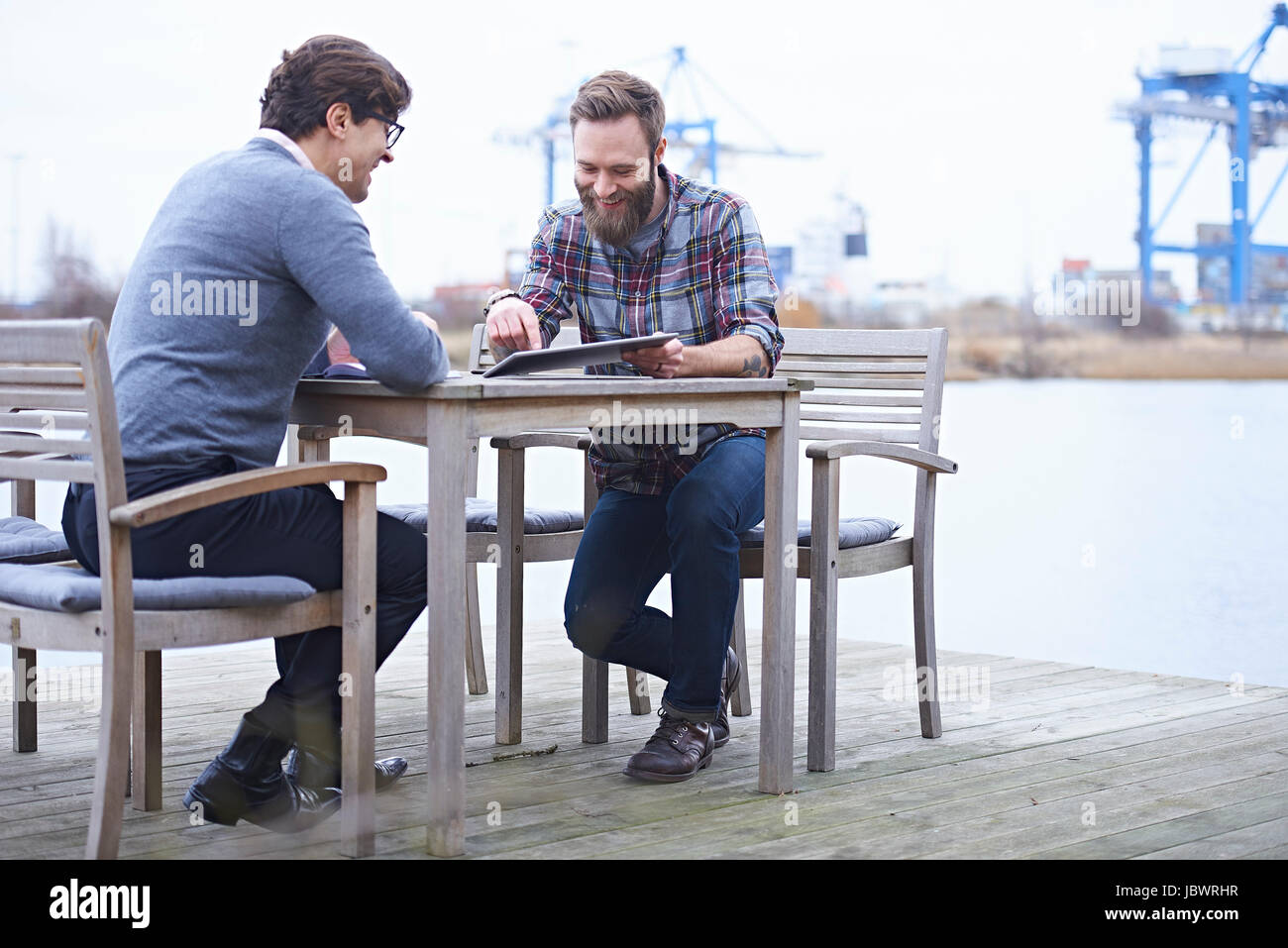 Two male designers having meeting on waterfront outside design studio ...