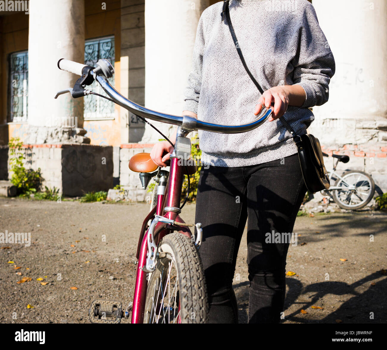 Neck down view of young woman with bicycle in urban area Stock Photo
