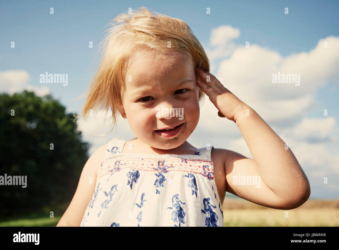 Portrait of female toddler in field with hand in blond hair Stock Photo