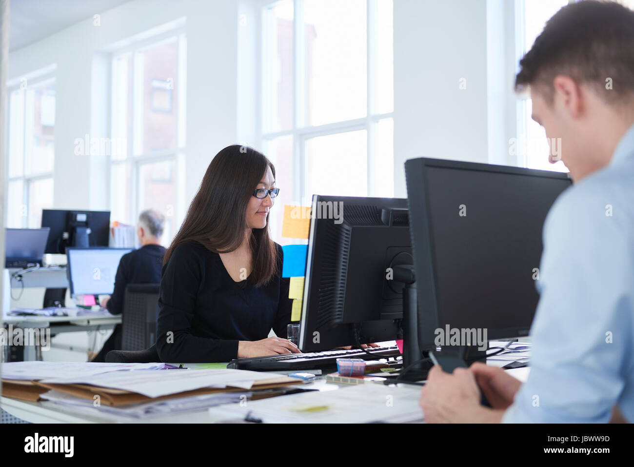Colleagues working in office, using computer Stock Photo - Alamy