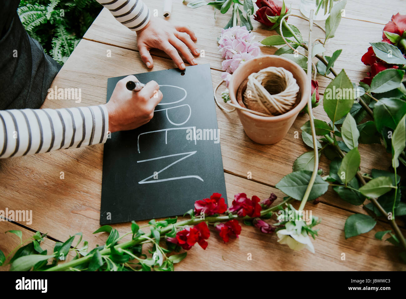 Florist in flower shop, writing 'Open' sign, mid section Stock Photo