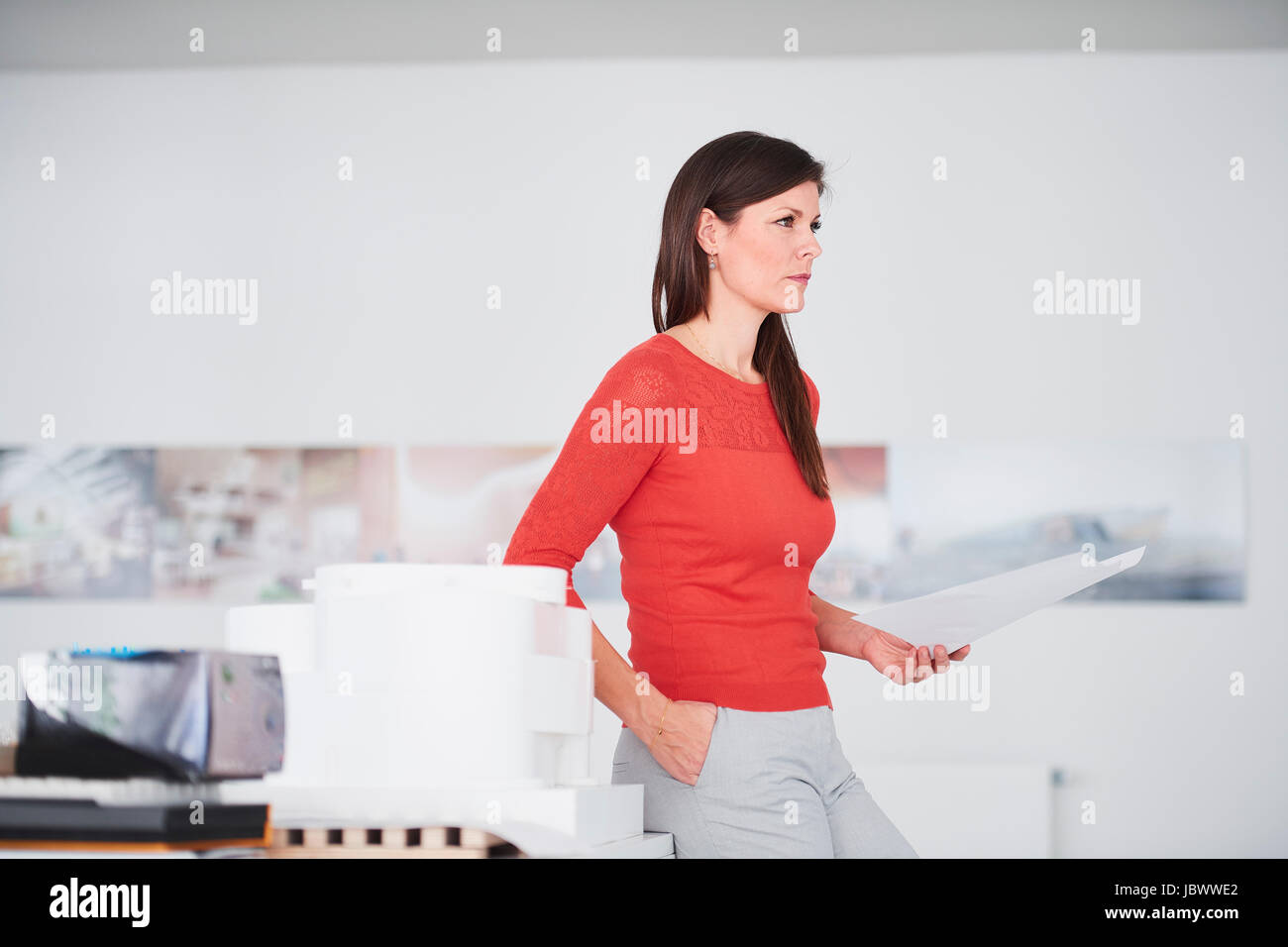 Businesswoman in office holding blueprints looking away Stock Photo