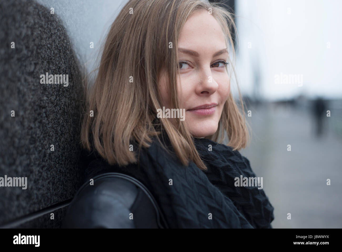 Portrait of young woman leaning against wall in city Stock Photo