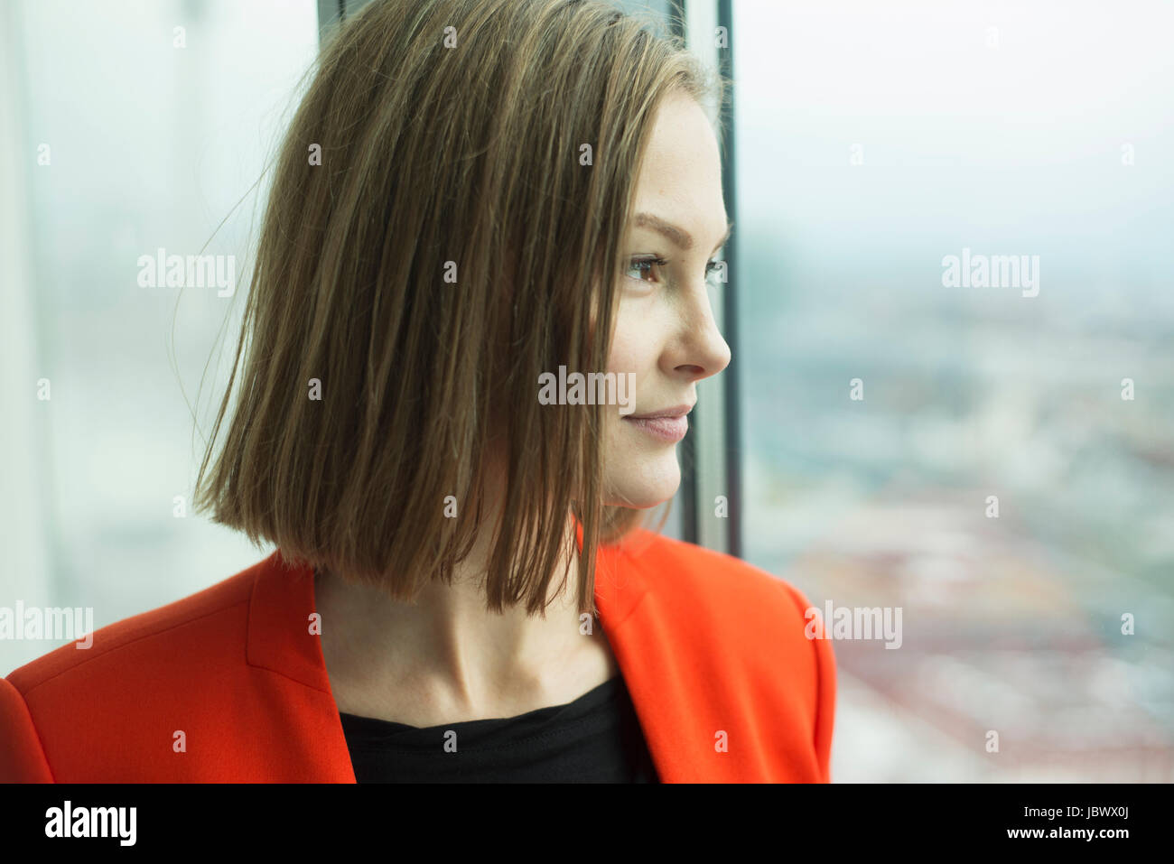 Young businesswoman gazing through office window Stock Photo