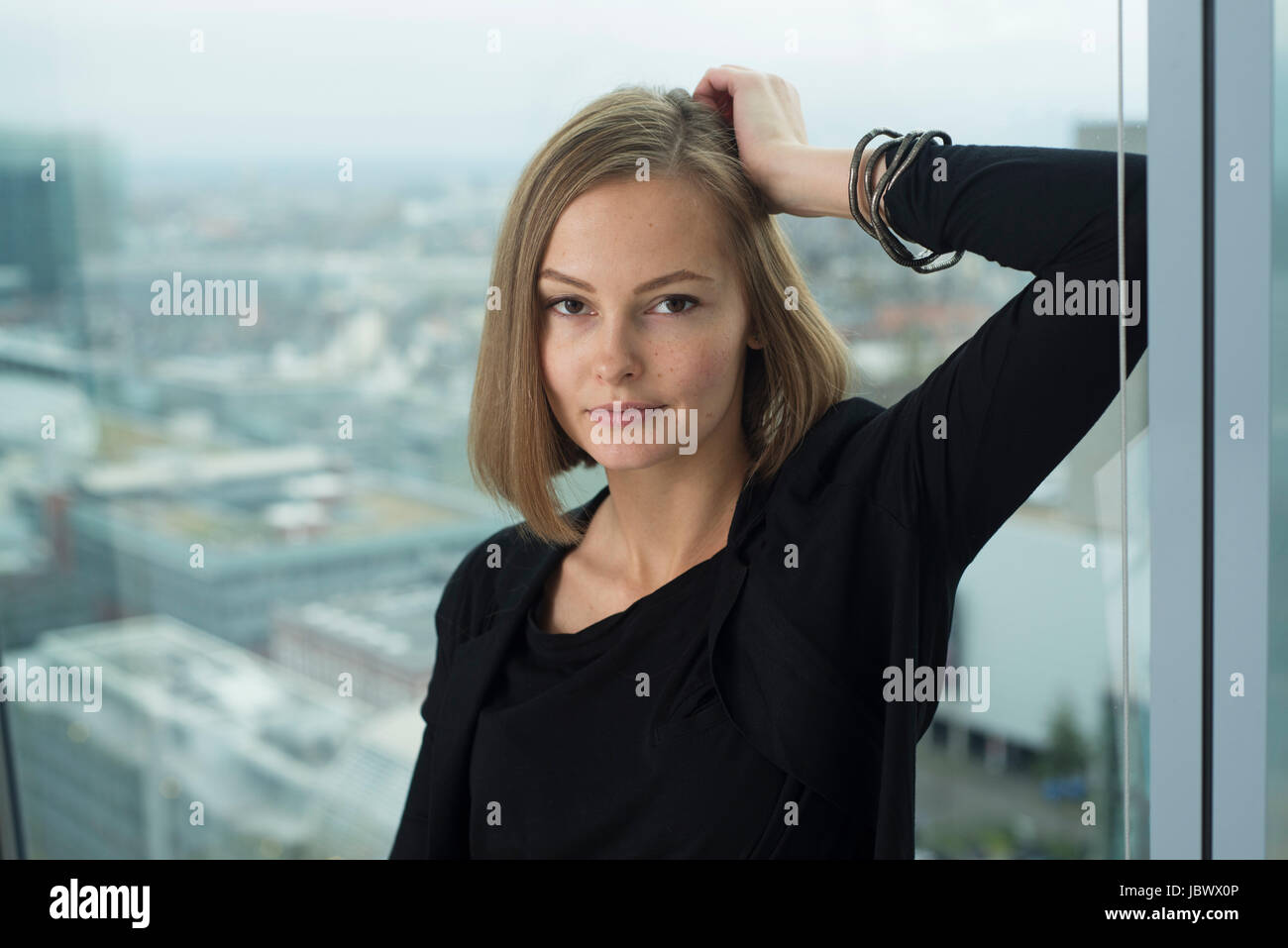 Portrait of confident young businesswoman leaning on  office window frame Stock Photo