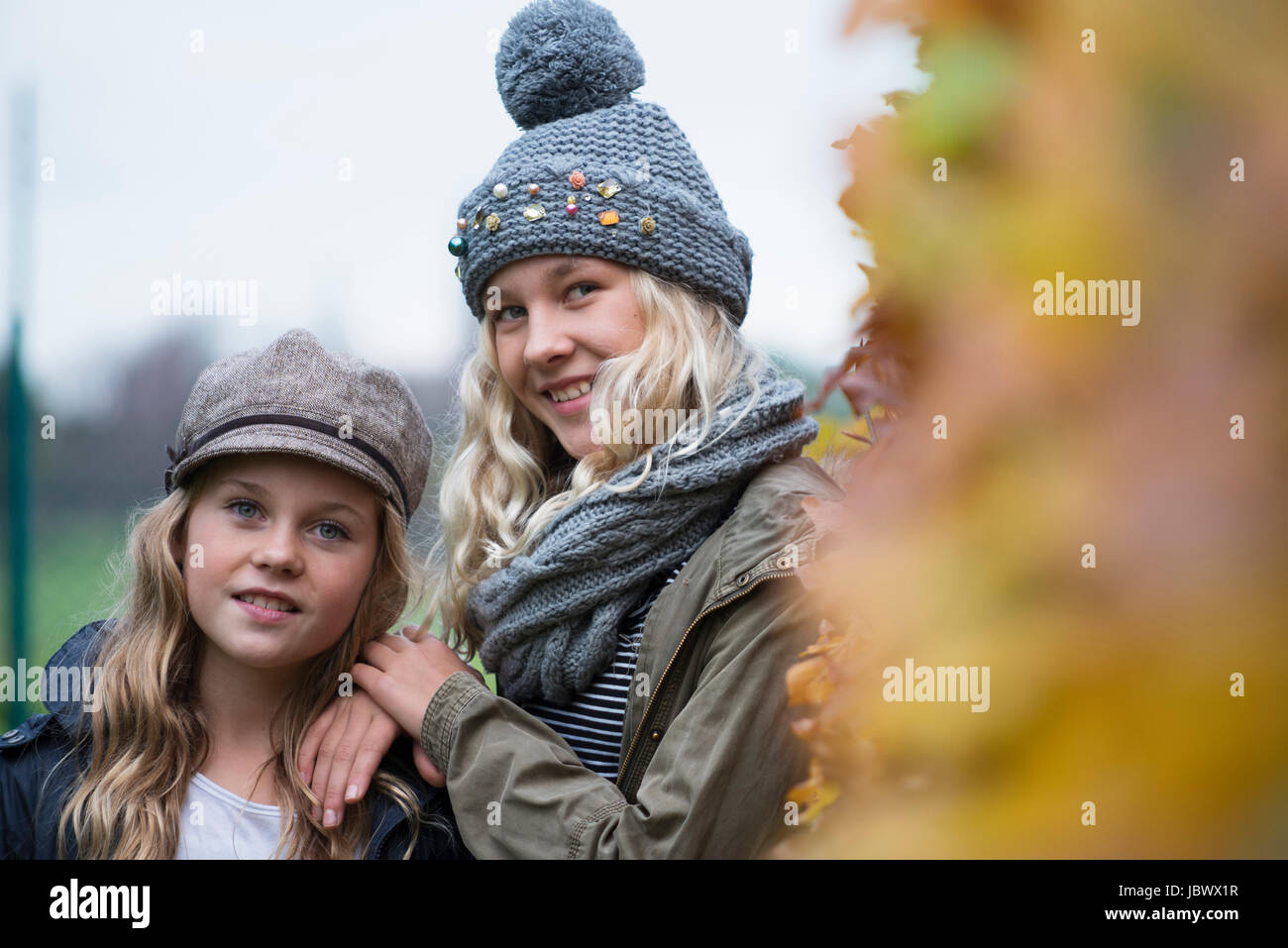 Portrait of two sisters in rural landscape wearing knit and baker boy hats Stock Photo