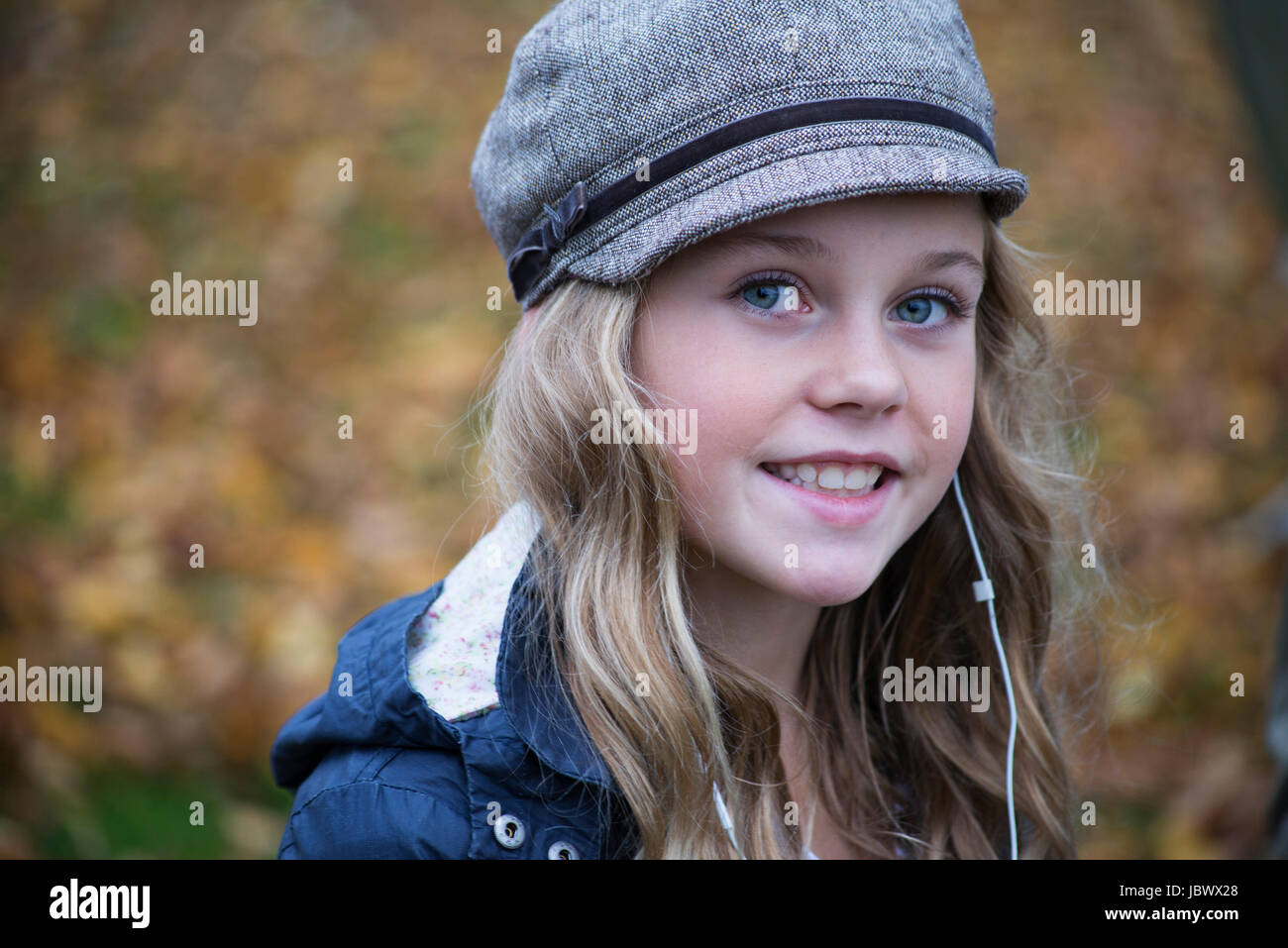 Portrait of blond girl in baker boy cap listening to earphone music Stock Photo