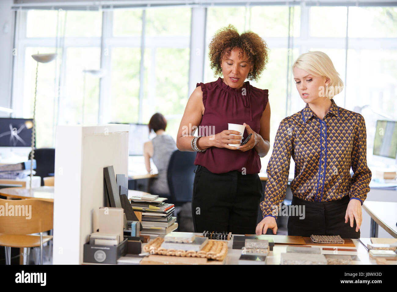Two female interior designers looking at swatches at office desk Stock Photo