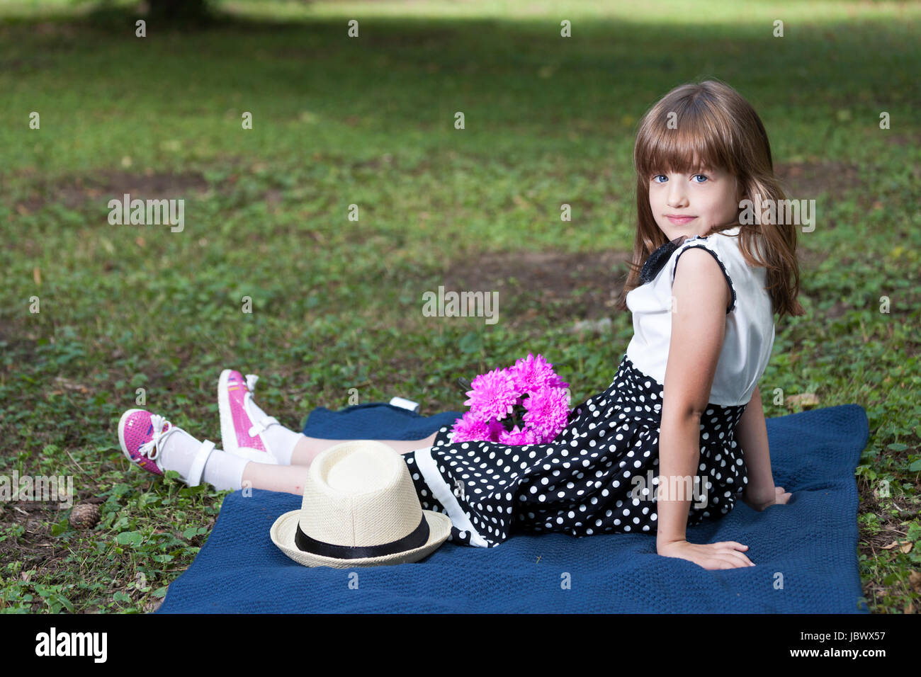 Portrait of a cute little girl with big blue eyes in a dress, sitting ...