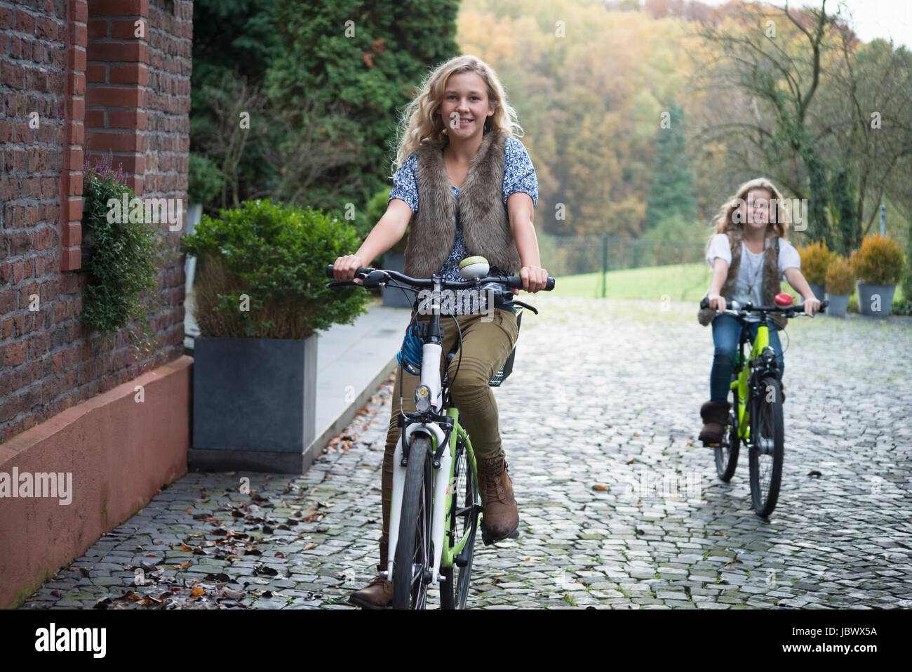 Two sisters cycling together in park Stock Photo