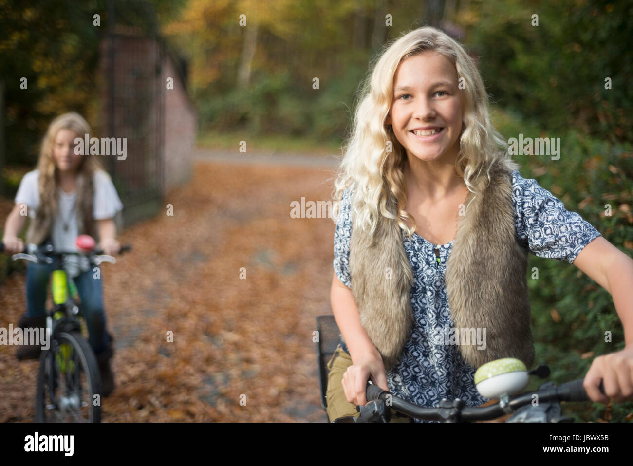 Portrait of two sisters cycling in autumn park Stock Photo