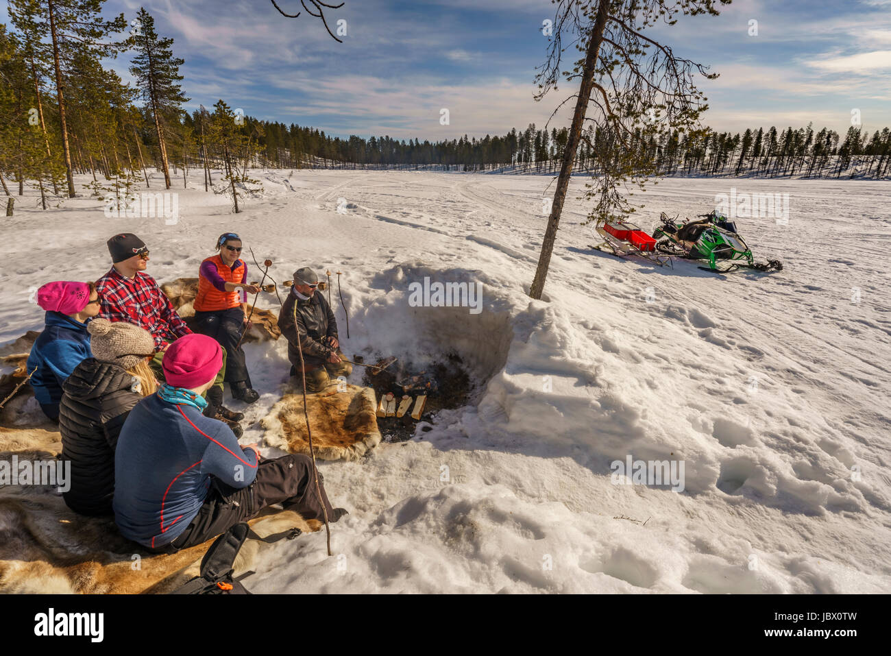 Tourists enjoying a snack by a campfire, Lapland Guesthouse, Kangos, Swedish, Lapland Stock Photo