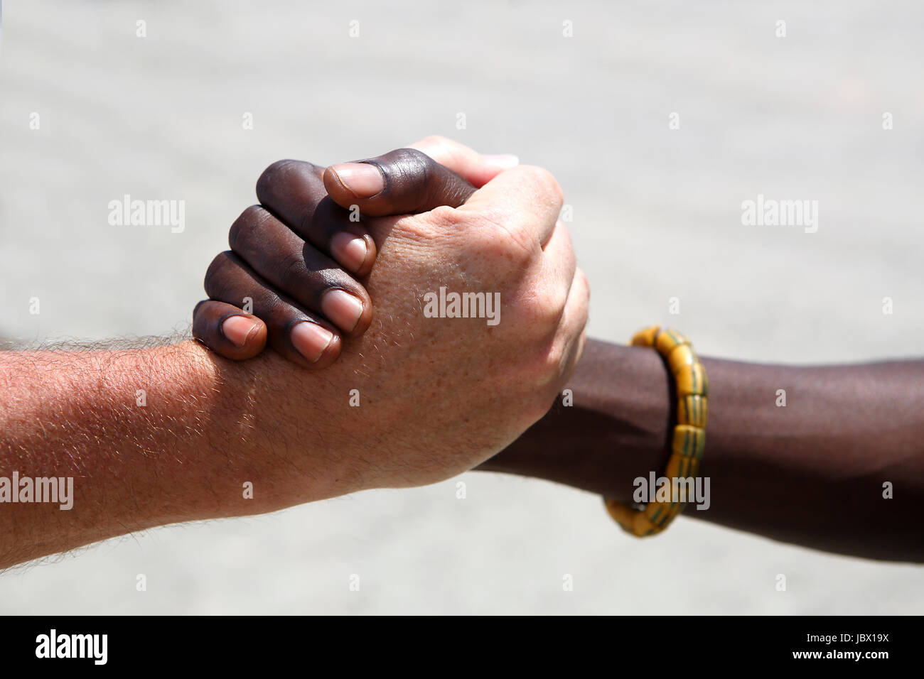 Handshake between a Caucasian and an African on gray background Stock Photo