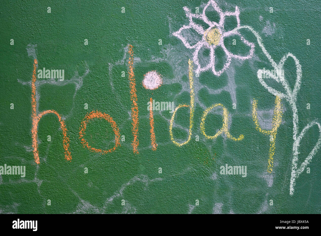 The word 'holiday' written on a green wall and a flower drawn next to it Stock Photo
