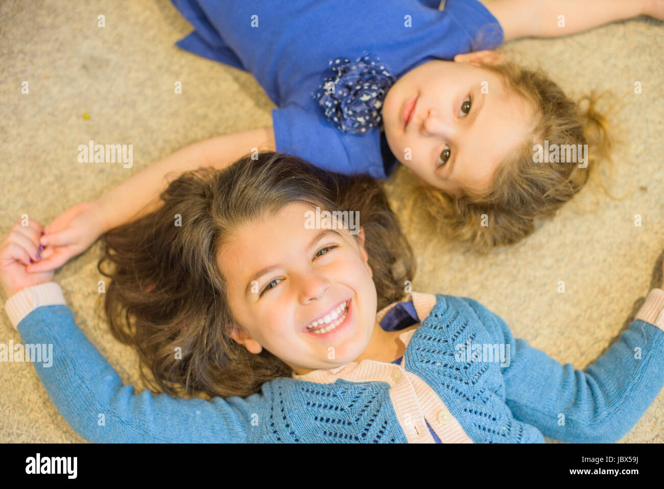 Sisters lying down on floor Stock Photo