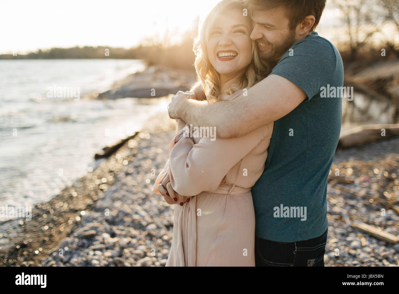 Couple beside lake, man hugging woman Stock Photo