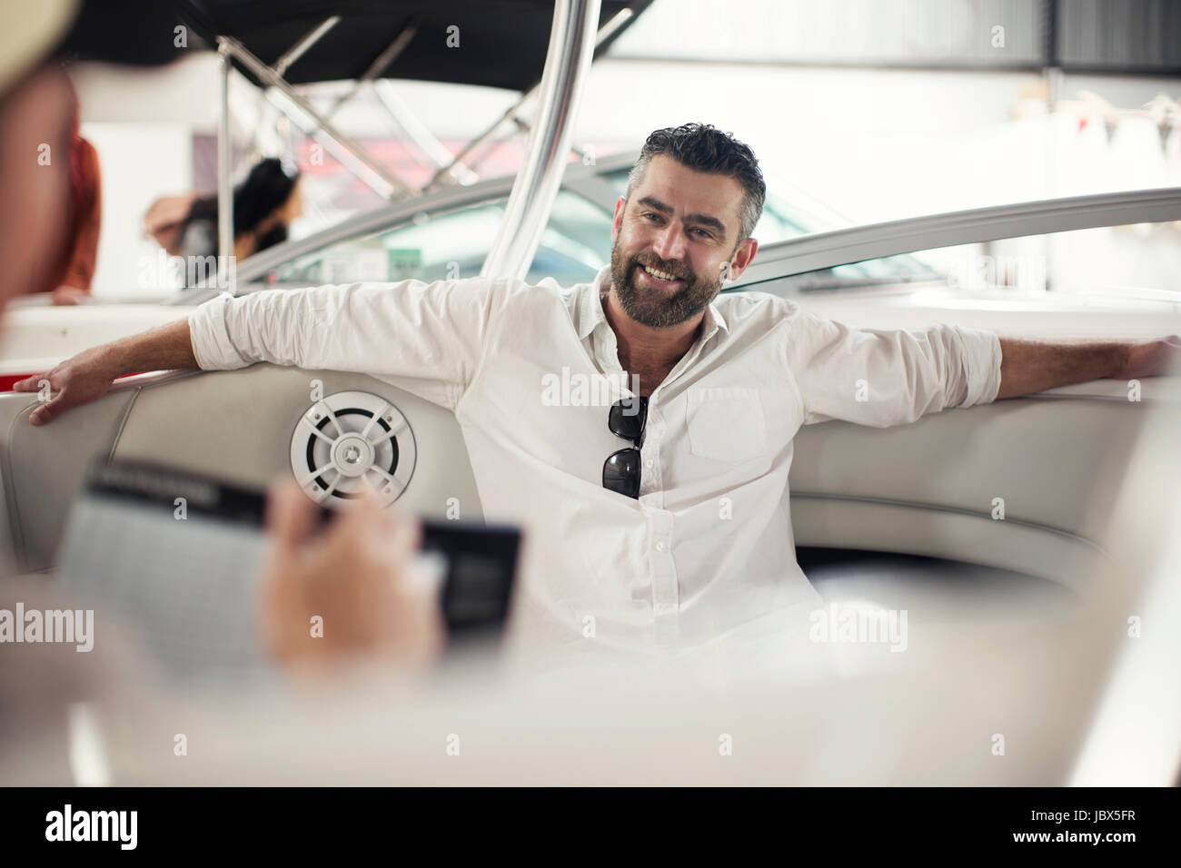 Over the shoulder view of man leaning against boat at repair workshop Stock Photo