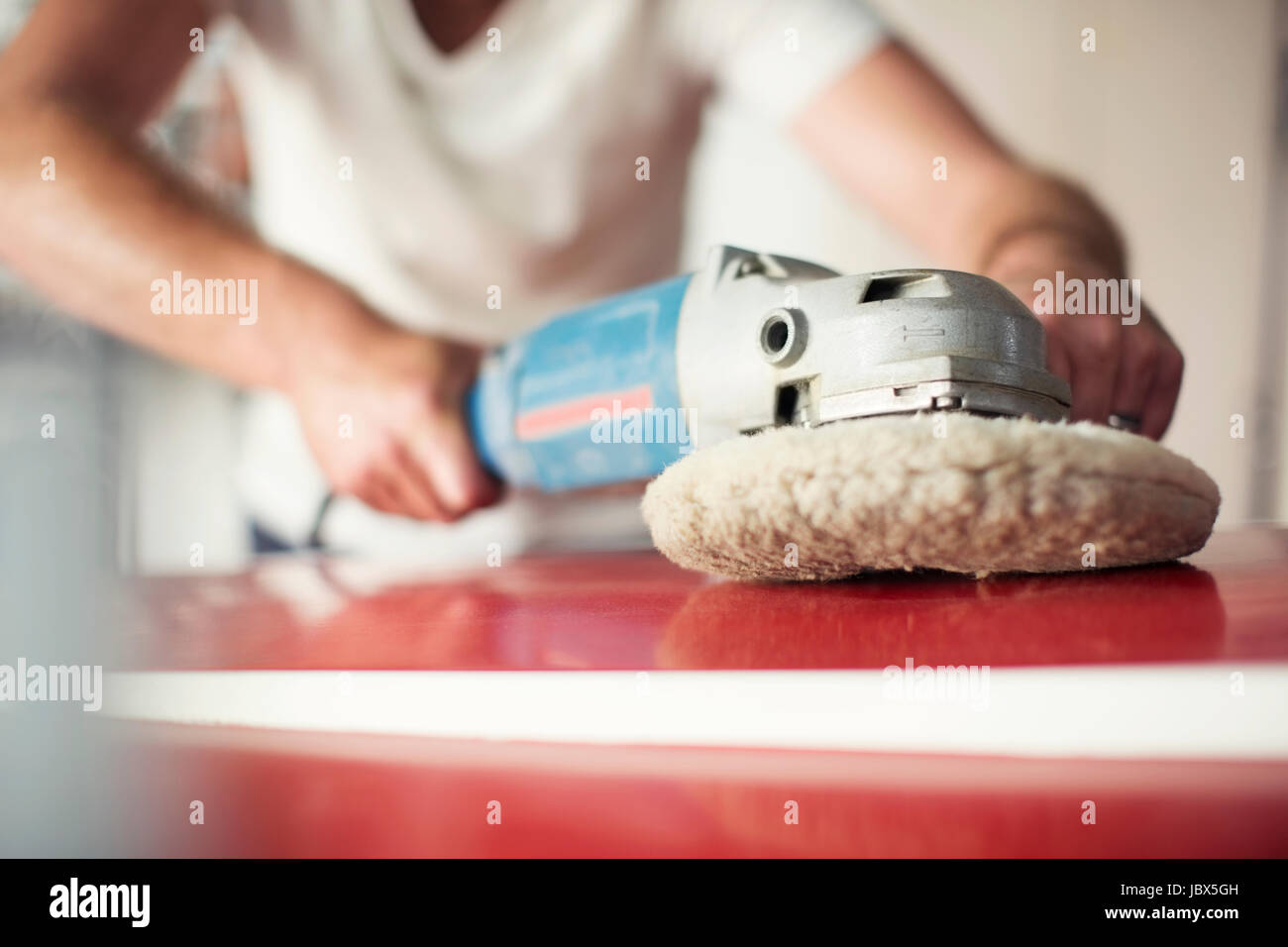 Mid section of man polishing boat in repair workshop Stock Photo