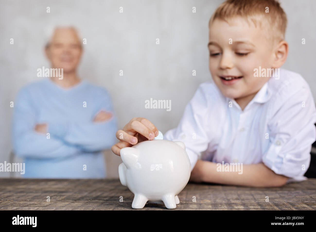 Cute excited boy putting a coin in a piggy bank Stock Photo - Alamy