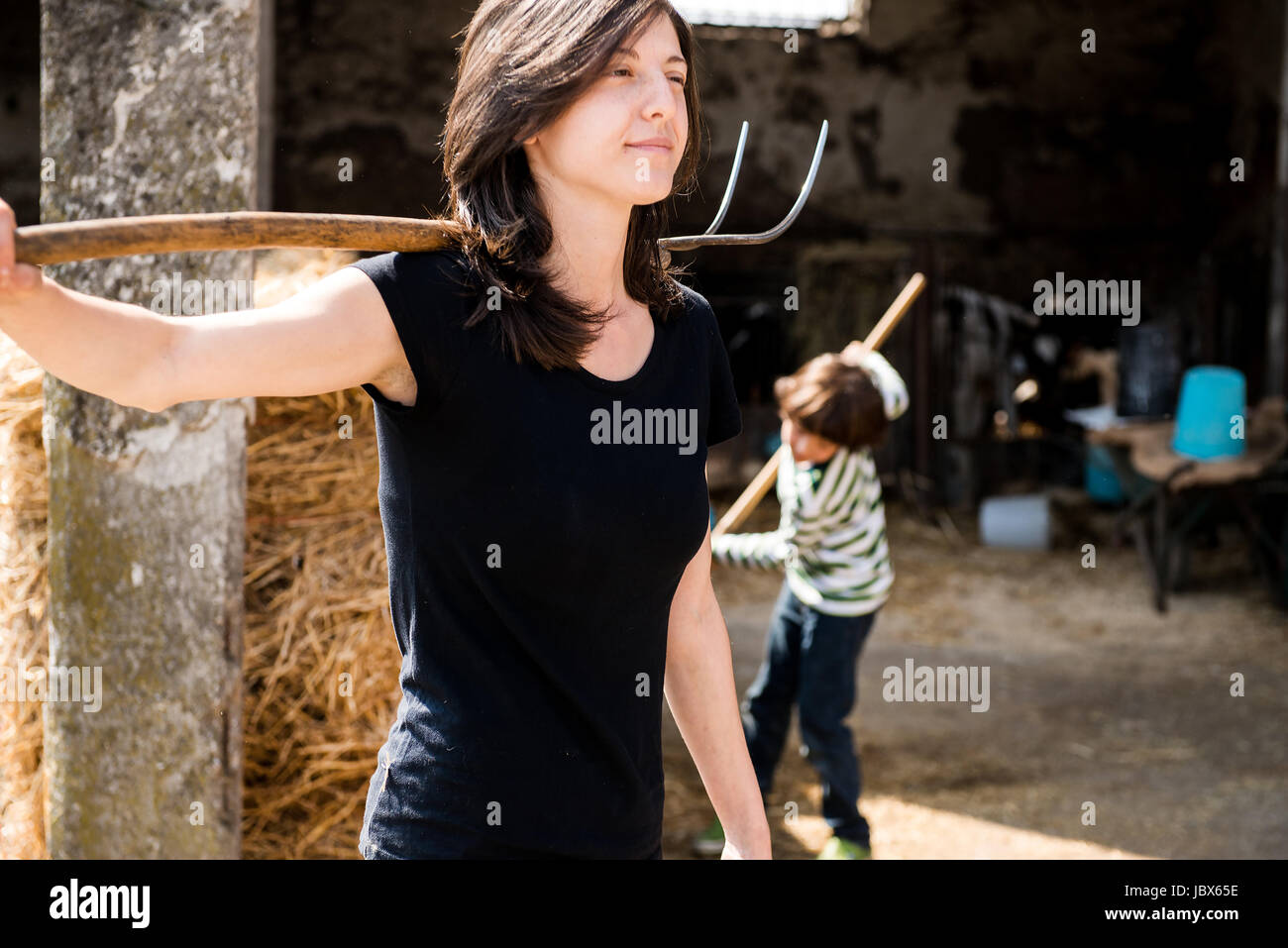 Female organic farmer with pitch fork over her shoulder on dairy farm Stock Photo