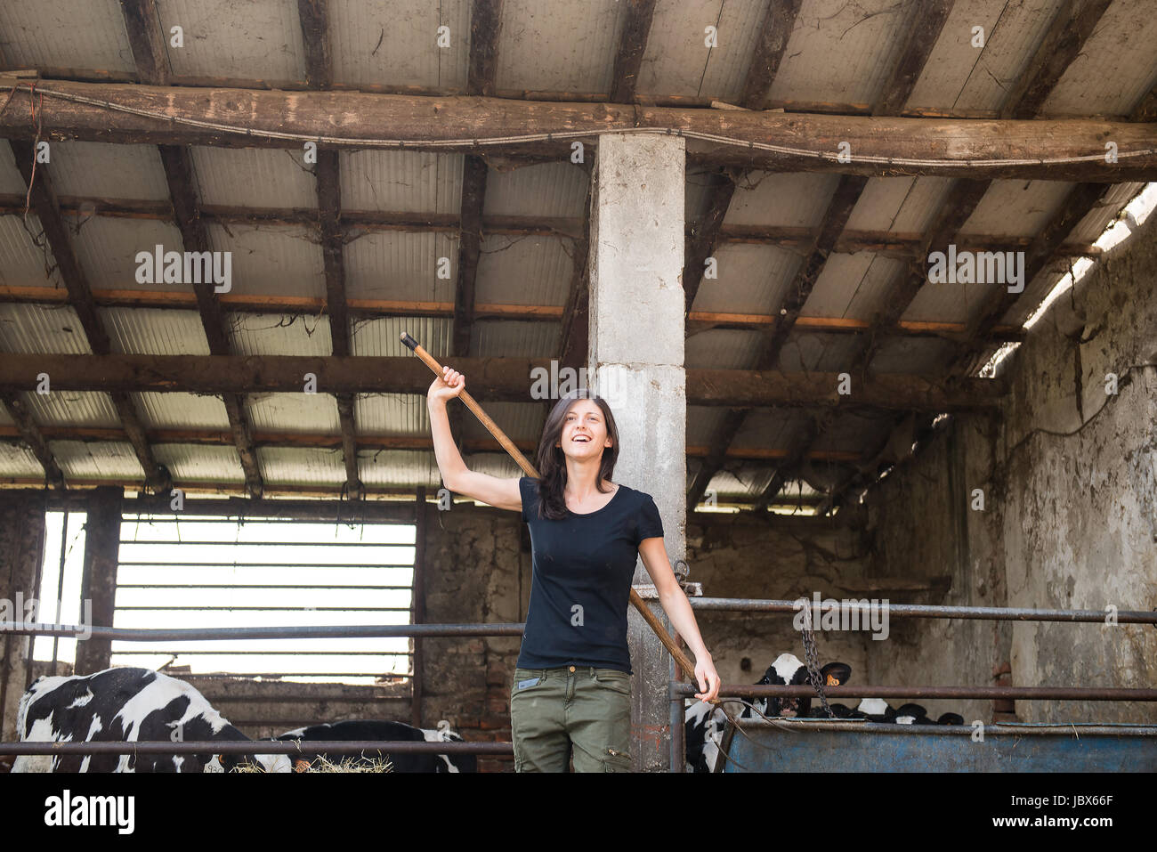 Female organic farmer with pitch fork over her shoulder on dairy farm Stock Photo