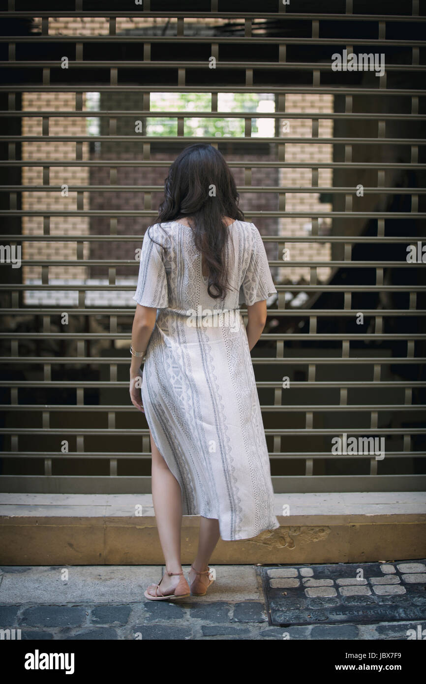 Rear view of a young woman with long dark hair standing outdoors Stock ...