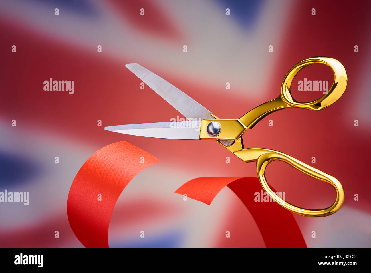 Golden scissors cutting red ribbon, symbolising brexit Stock Photo - Alamy