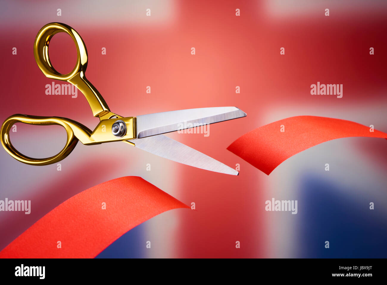 Golden scissors cutting red ribbon, symbolising brexit Stock Photo