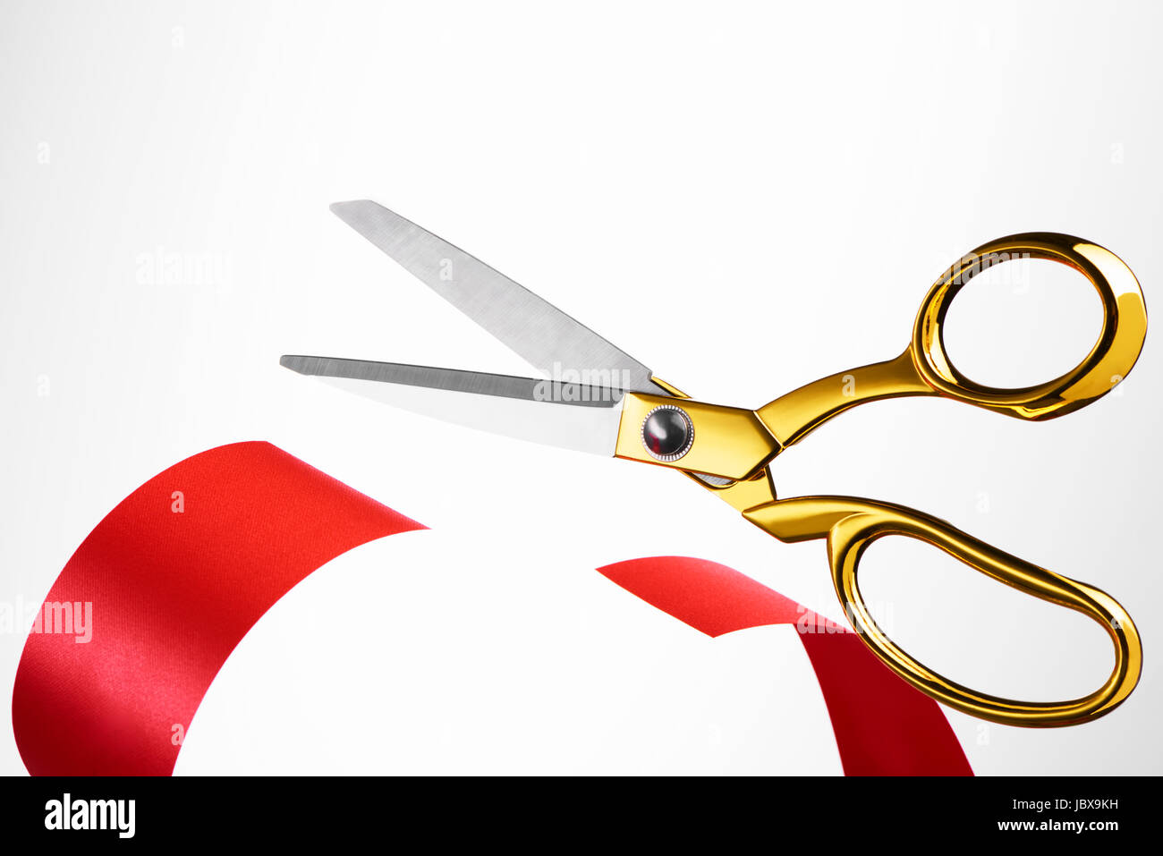 Golden scissors cutting red ribbon/ tape Stock Photo