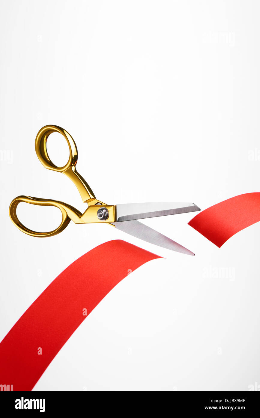 Golden scissors cutting red ribbon/ tape Stock Photo