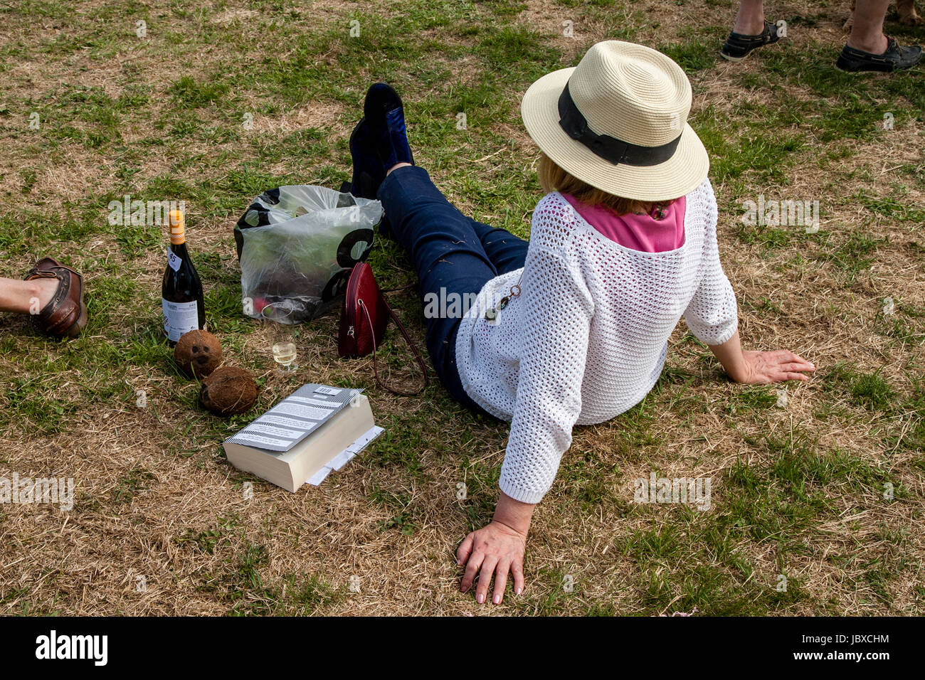 A Woman Sitting Down On The Rectory Field At The Jevington Fete, Jevington, East Sussex, UK Stock Photo