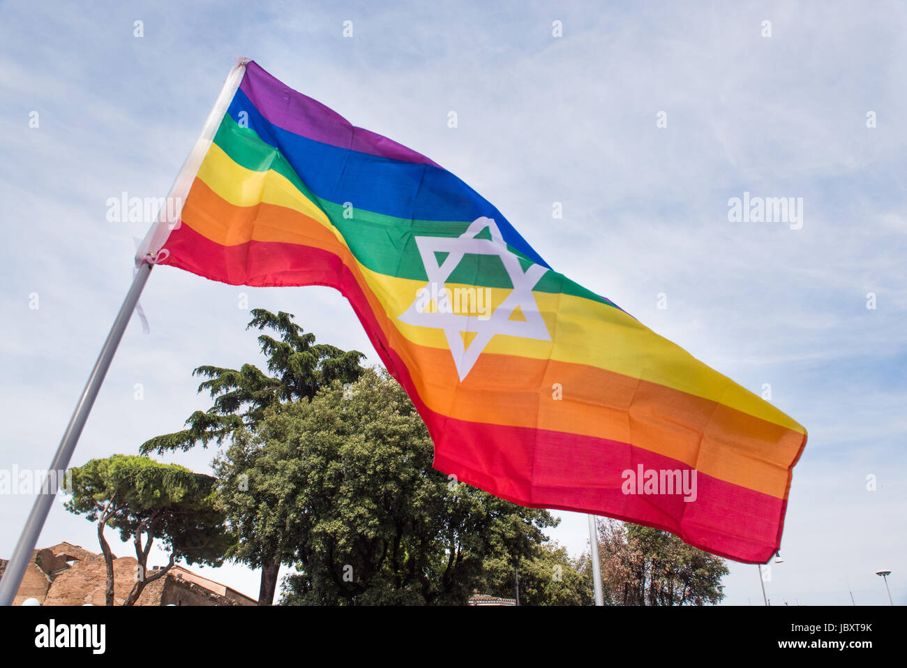 Colorful rainbow peace flag with star of david hexagon symbol over sky Stock Photo