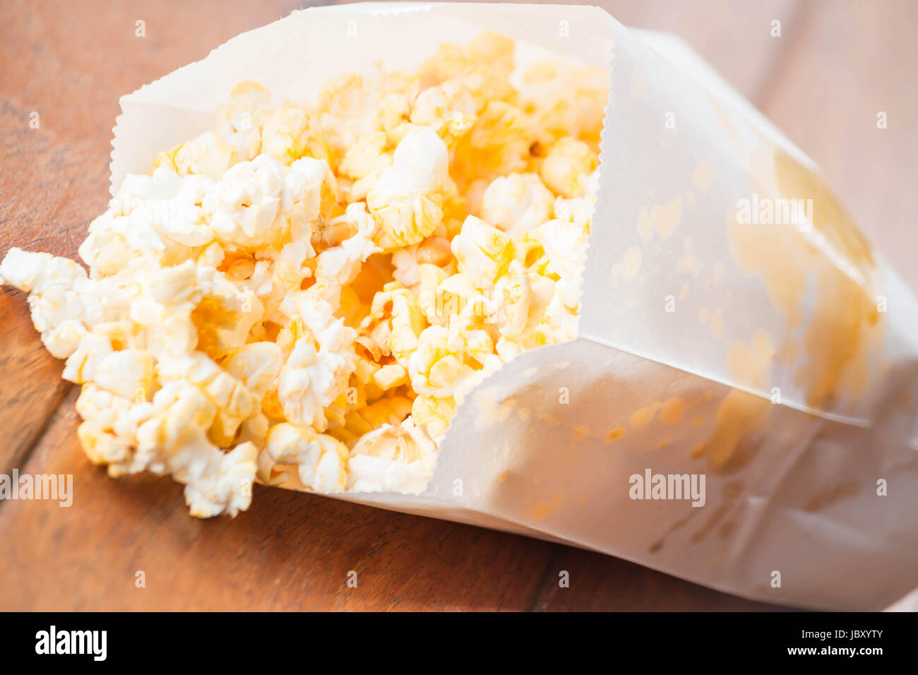 Popcorn packet opened with corn spilling out Stock Photo Alamy
