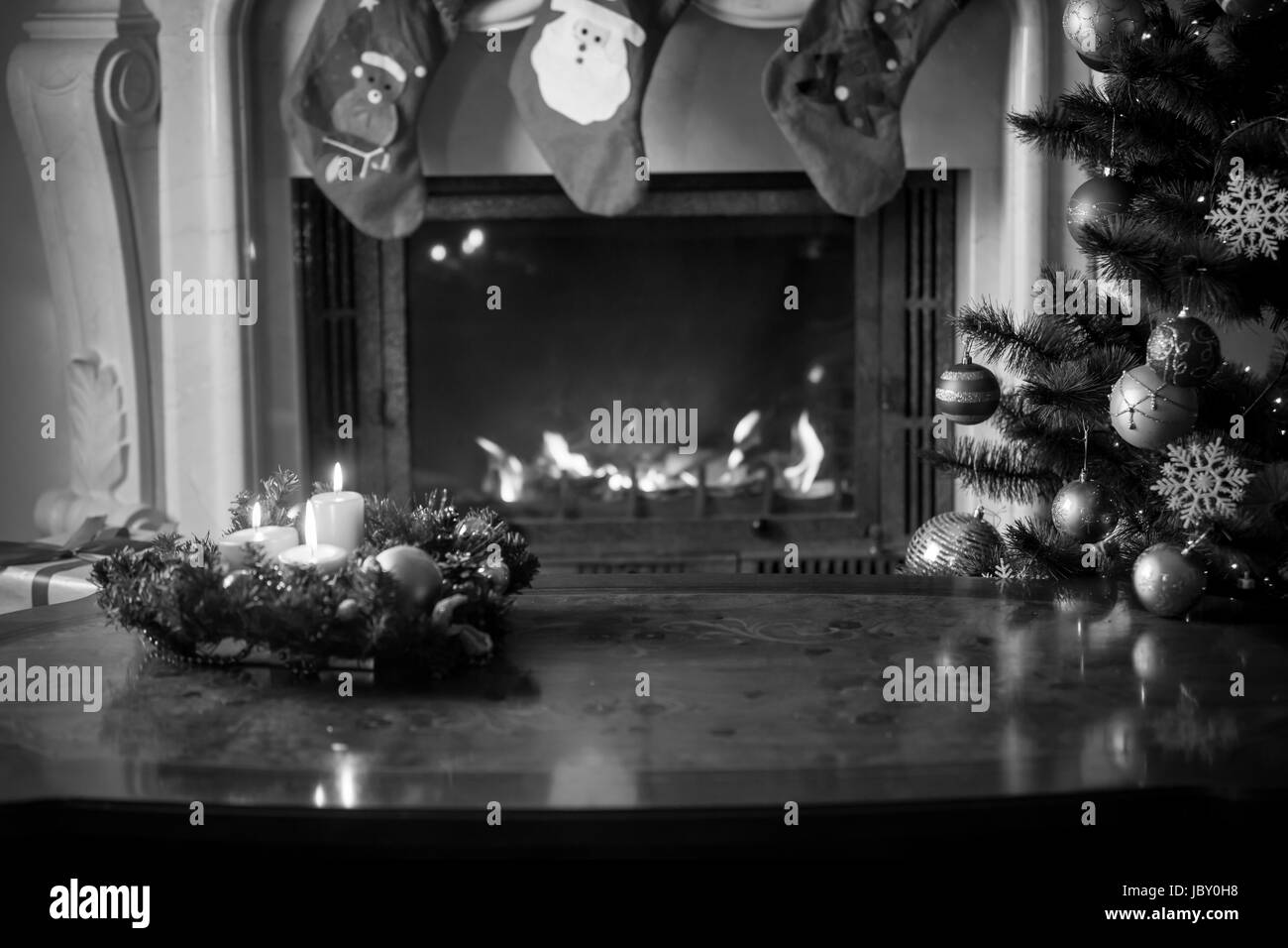 Black and white background with wooden table in front of burning fireplace, burning fireplace and Christmas tree Stock Photo