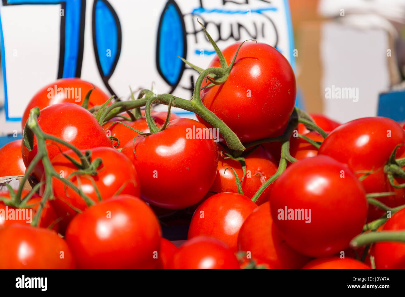 Display of pile of shiny red vine tomatos on sale at fruit and ...