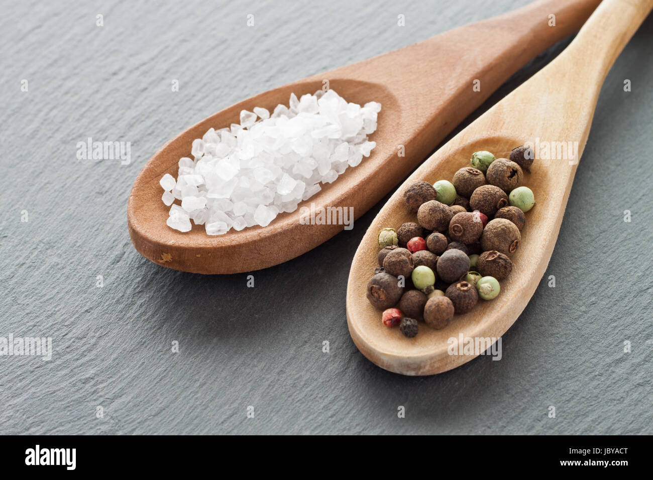 Meersalz und Pfefferkörner auf Holzlöffeln Stock Photo