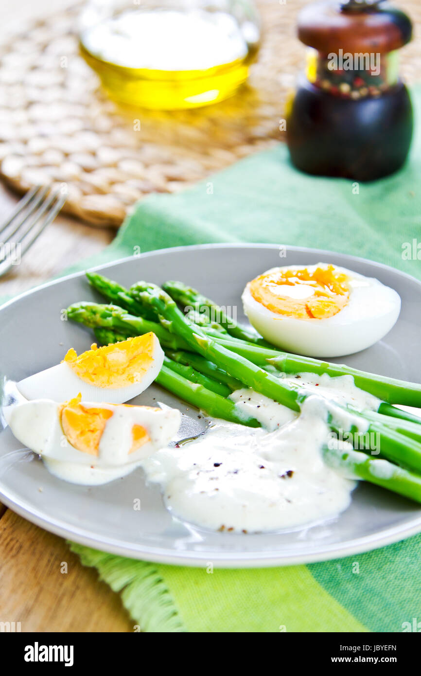 Steamed Asparagus with boiled eggs and sour cream dressing Stock Photo