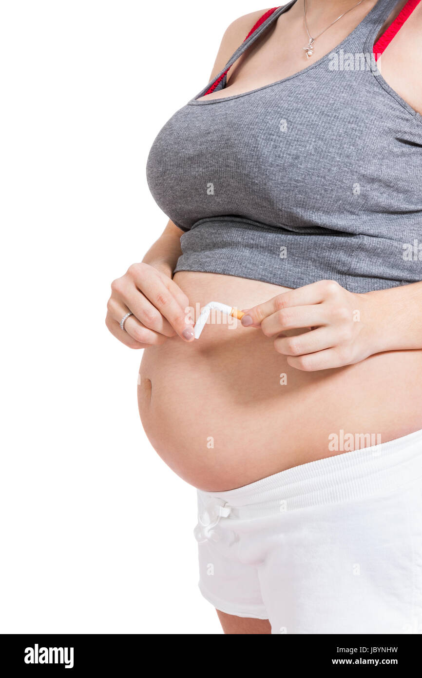 schwangere Frau zerbricht eine Zigarette vor Ihrem Babybauch isoliert vor weißem Hintergrund Stock Photo