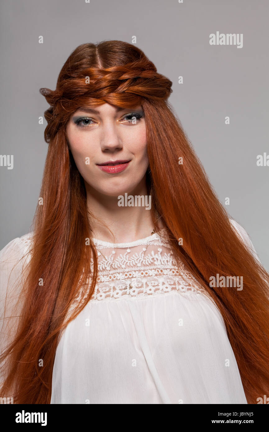 Junge attraktive Fraumädchen mit langen roten haaren im Portrait vor grauem Hintergrund Stock