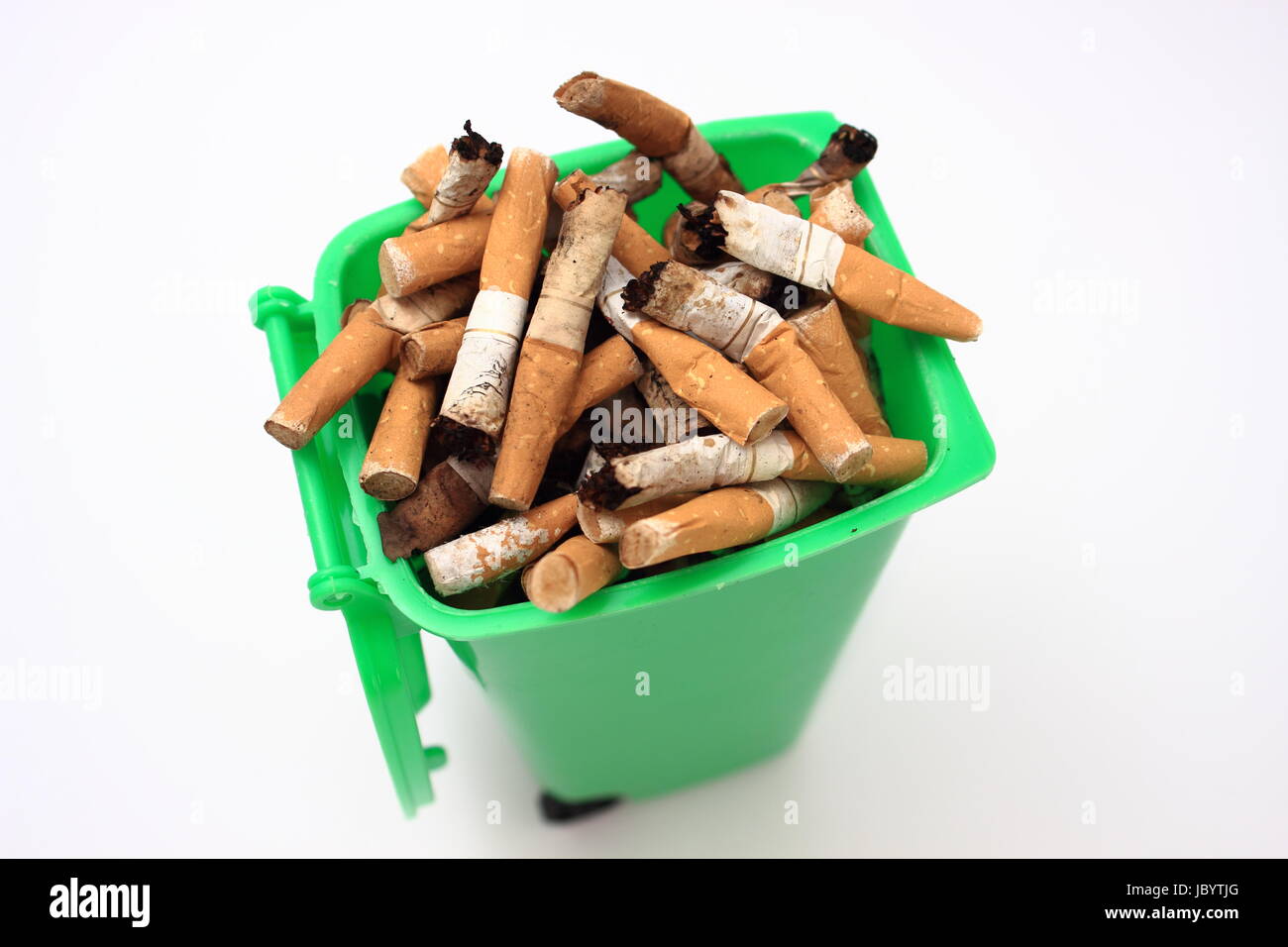 Used cigarette butts in green waste bin on white background Stock Photo
