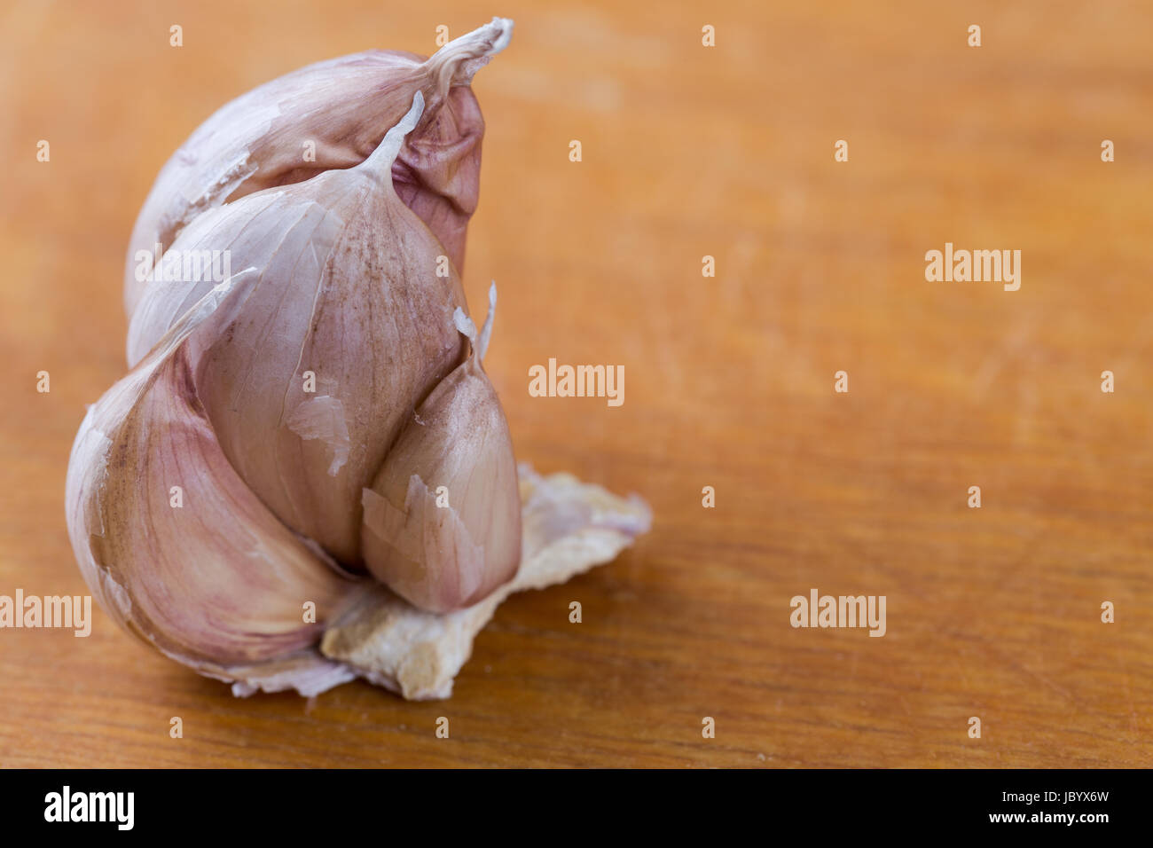 cloves of garlic on scratched yellow wooden background Stock Photo - Alamy