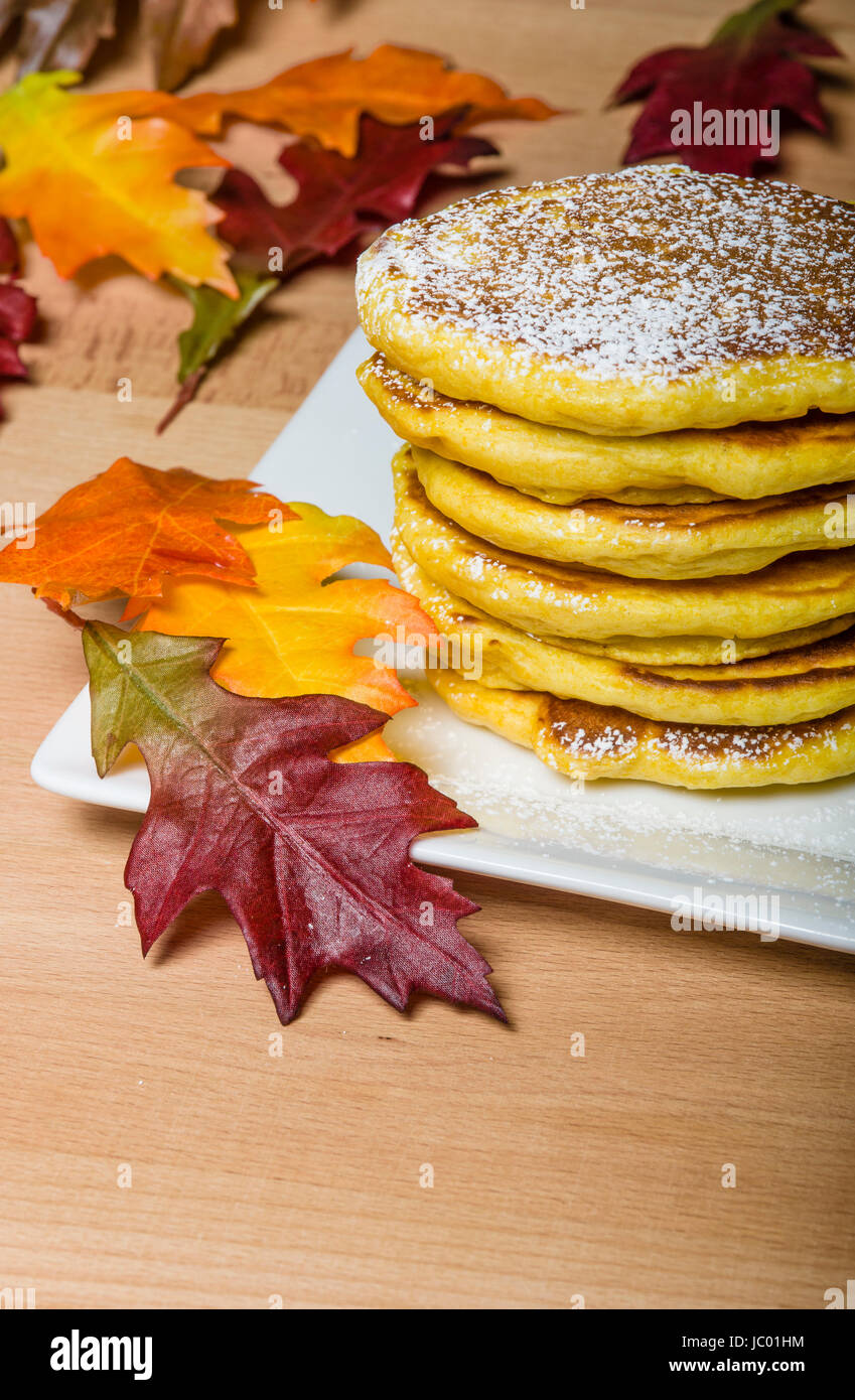 Fresh pancakes topped with powdered sugar with fall leaves Stock Photo