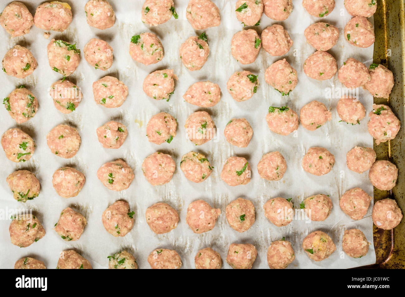 Freshly formed raw meatballs with herbs on oven pan ready to bake Stock