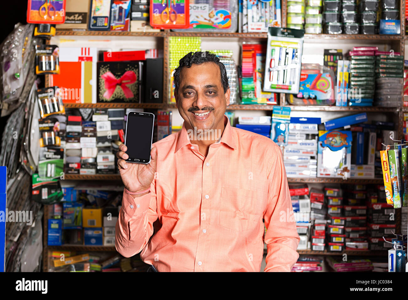 1 Indian Shop Keeper Man Showing New Smartphone In Stationary Shop Stock Photo