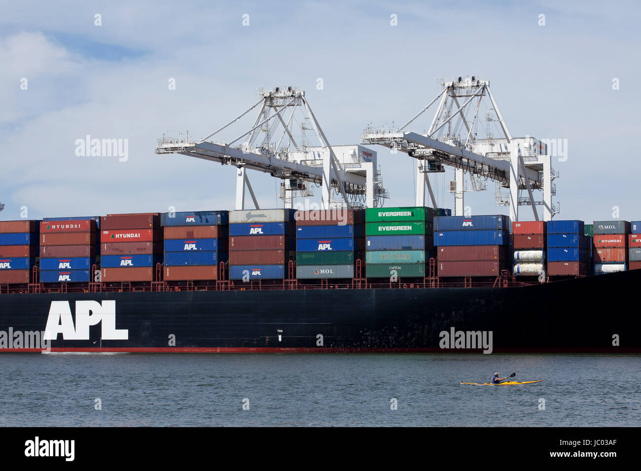 Man kayaking by APL shipping container ship docked Port of Oakland - California USA Stock Photo