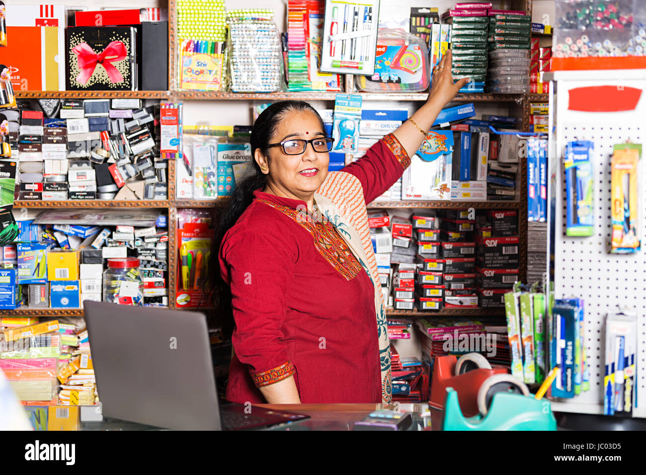 1 Indian Shop Keeper Woman Arranging Product On rack In Stationary Shop Stock Photo