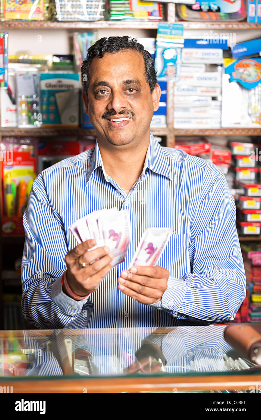 1 Indian Shop Keeper Man Standing Counter and Counting Money Cash In Stationary Shop Stock Photo