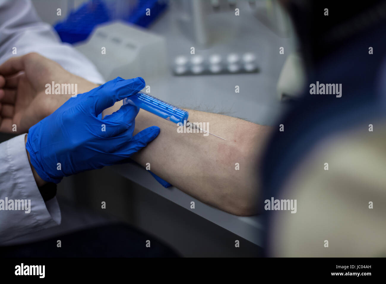 Doctor or scientist inject a needle in patient's arm Stock Photo - Alamy